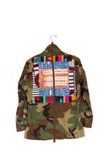 Camouflage jacket with colorful patchwork design on a hanger against an orange wall