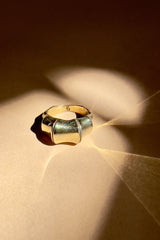 Gold ring on a textured surface with light casting shadows
